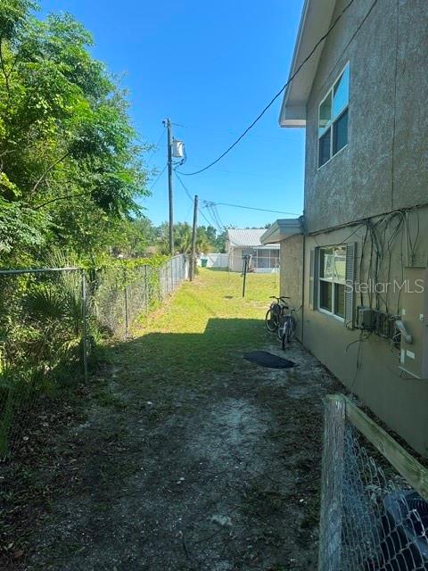 A side yard view shows a house exterior, a chain-link fence, and a parked bicycle — 112 CARIBBEAN STREET, DELTONA, FL