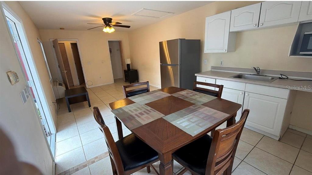 A dining area with a wooden table and chairs sits next to a small kitchen — 226 ORCHID DRIVE, DAVENPORT, FL