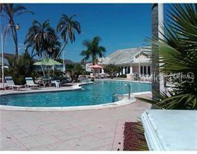 An outdoor swimming pool surrounded by a patio, lounge chairs, palm trees, and a building — 226 ORCHID DRIVE, DAVENPORT, FL