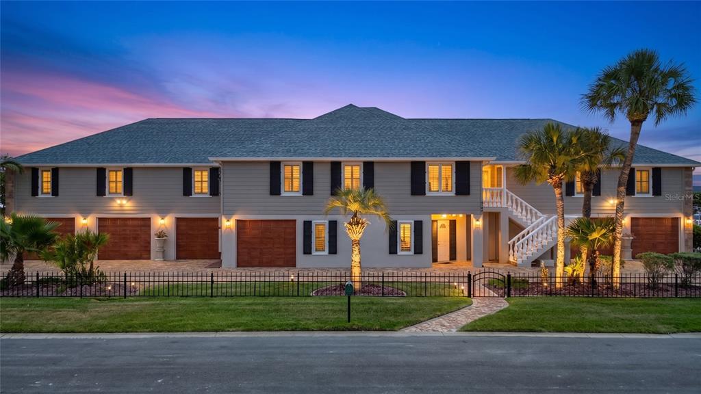 A two-story house with a gray exterior, multiple garage doors, and a white staircase at dusk — 4146 DIAZ COURT, HERNANDO BEACH, FL