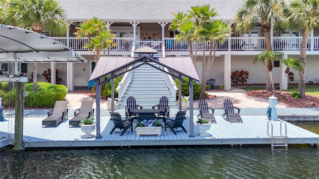 A wooden dock with a metal gazebo, patio furniture, and stairs leading to a building — 4146 DIAZ COURT, HERNANDO BEACH, FL