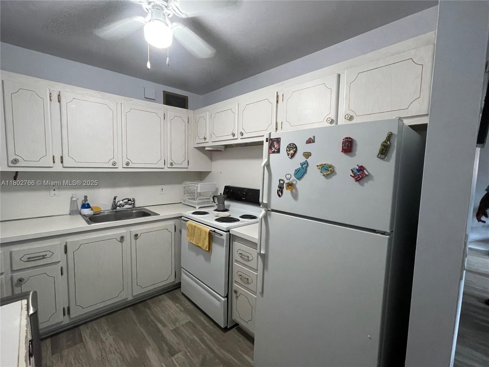A kitchen features white cabinets, a white stove, a white refrigerator, and wood-look flooring — 279 Markham M # M, Deerfield Beach FL 33442, DEERFIELD BEACH, FL