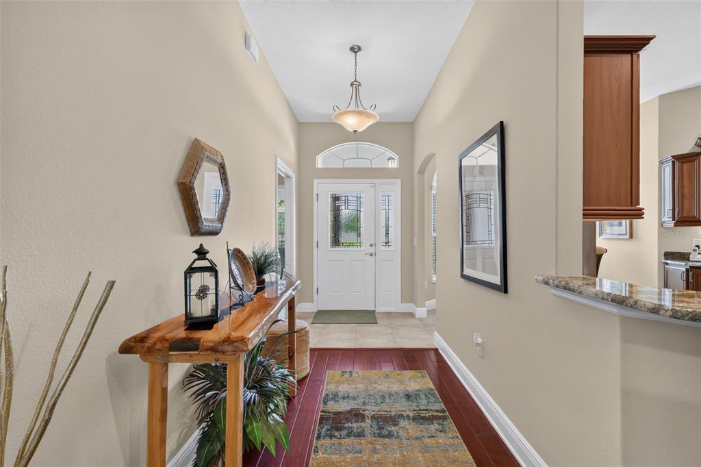 A foyer features a wooden console table, a patterned rug, and a white front door — 1583 LEMON LOOP, THE VILLAGES, FL