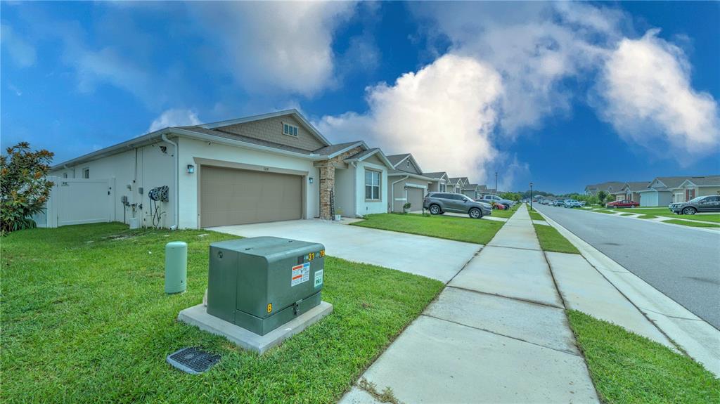 A suburban street view shows a single-story house with a garage and a green utility box — 1228 MATTIE POINTE BOULEVARD, AUBURNDALE, FL