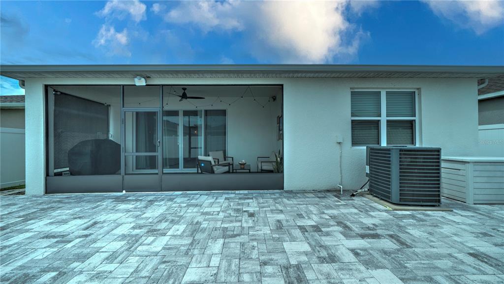 A paved patio sits outside a house with a screened-in porch and an air conditioning unit — 1228 MATTIE POINTE BOULEVARD, AUBURNDALE, FL