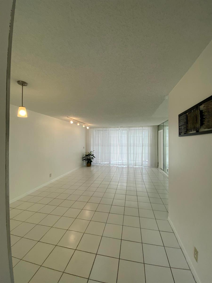 An empty room with white tile floors, white walls, and a large sliding glass door — 4110 Tivoli Court # 103, FL 33467, FL