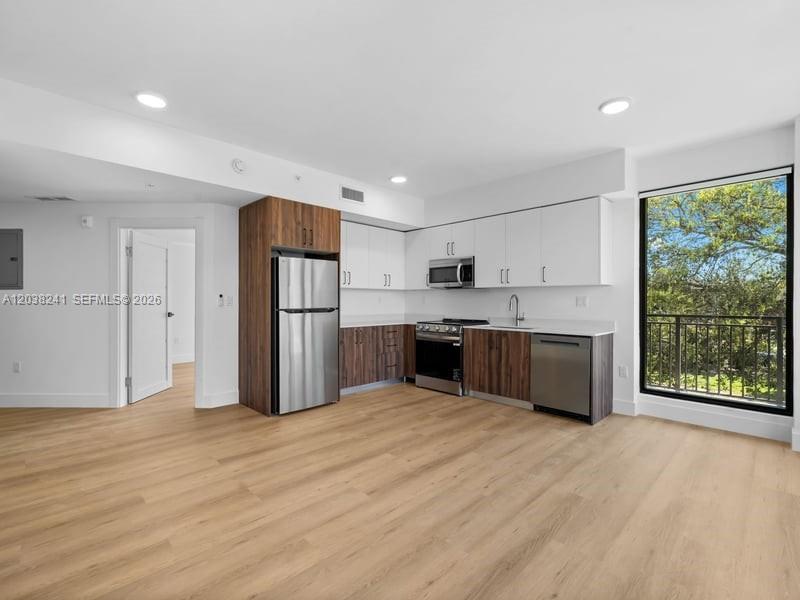 A kitchen with wood-tone lower cabinets, white upper cabinets, stainless steel appliances, and wood flooring — 2479 NE 192nd St # 308, Miami FL 33180, MIAMI, FL