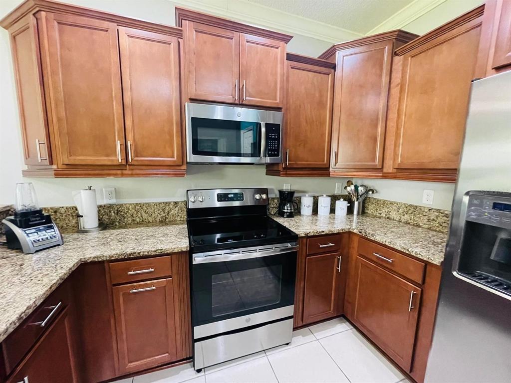 A kitchen features wood cabinets, granite countertops, and stainless steel appliances — 1743 PORTOFINO MEADOWS BOULEVARD, ORLANDO, FL