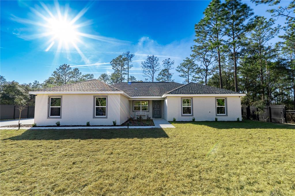 A single-story house with a light-colored exterior, dark roof, and a front lawn — 6920 SW 209TH AVENUE, DUNNELLON, FL