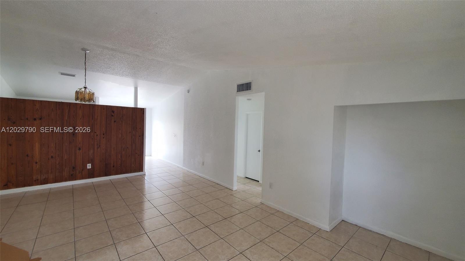 A room with light-colored tile flooring, white walls, and a wood-paneled accent wall — 18047 NW 41ST PL # 0, Miami FL 33055, MIAMI, FL