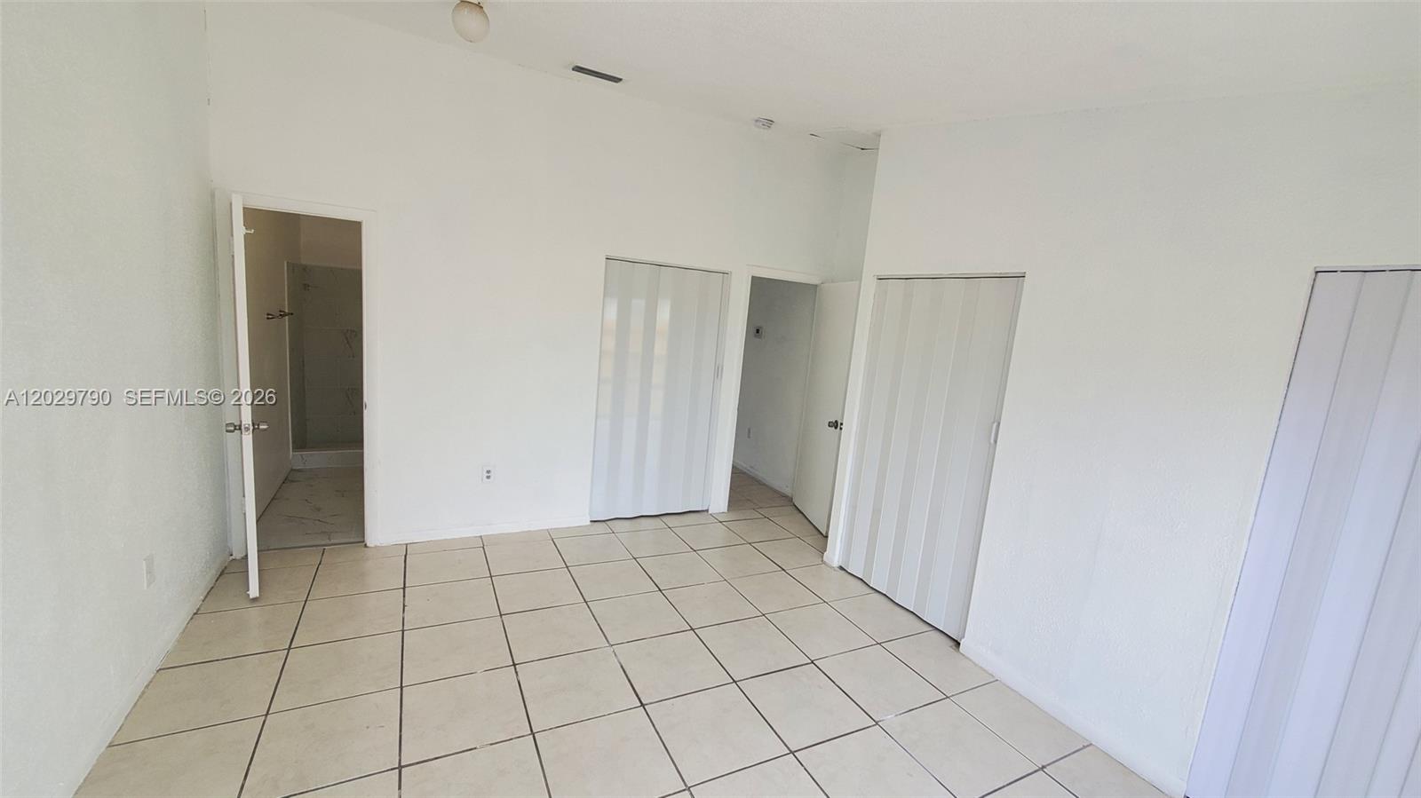 An empty room features white walls, tiled flooring, and multiple closet doors — 18047 NW 41ST PL # 0, Miami FL 33055, MIAMI, FL