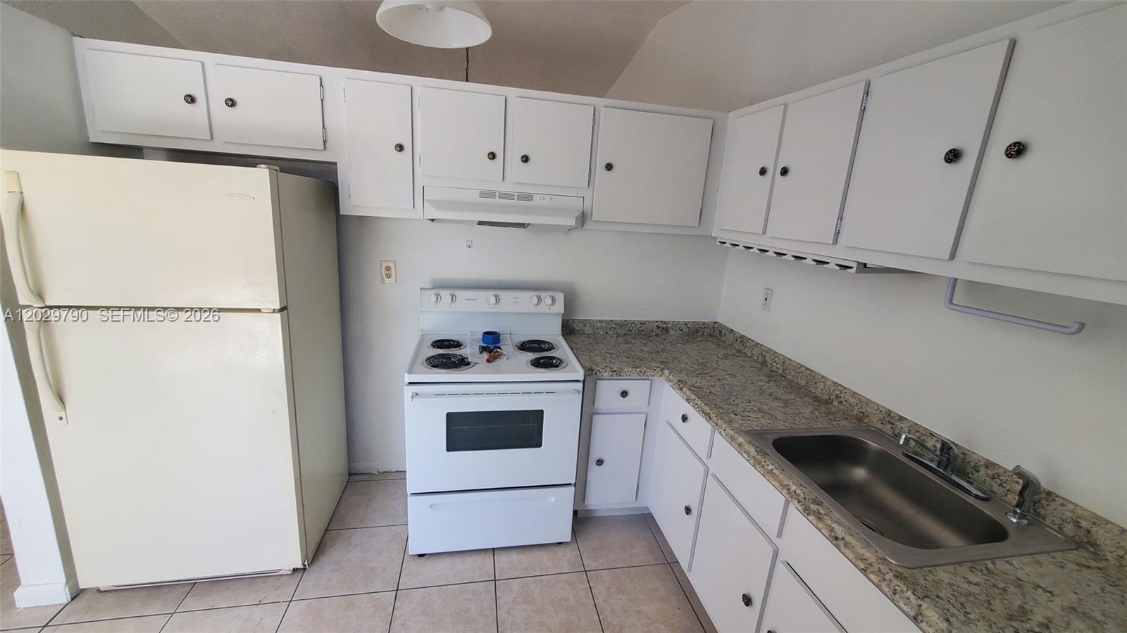 A kitchen features white cabinets, a white stove, a refrigerator, and speckled granite countertops — 18047 NW 41ST PL # 0, Miami FL 33055, MIAMI, FL