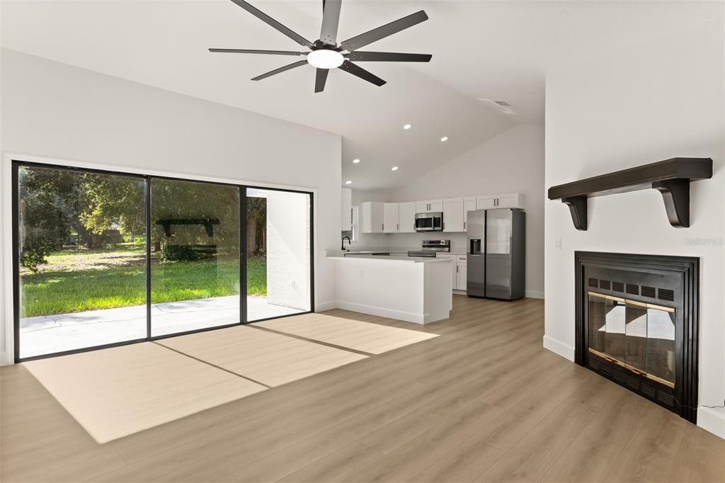A living room with light wood flooring, a fireplace, and sliding glass doors to a yard — 7336 BORDWINE DRIVE, ORLANDO, FL