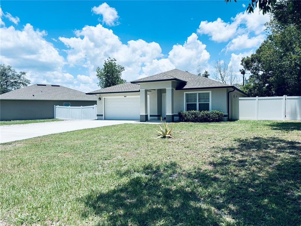 A single-story house with a white garage, beige exterior, and a white vinyl fence — 2060 EVEREST STREET, DELTONA, FL