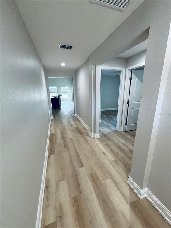 A hallway with light wood-look flooring leads toward an open living area and side rooms — 2060 EVEREST STREET, DELTONA, FL
