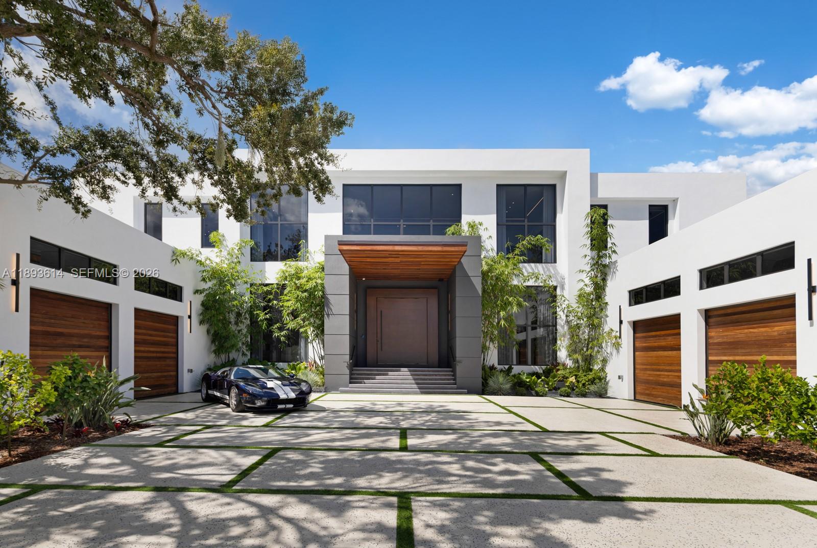 A modern two-story house features a wooden front door, a paved driveway, and a sports car — 9900 SW 125th Ave, Miami FL 33186, MIAMI, FL