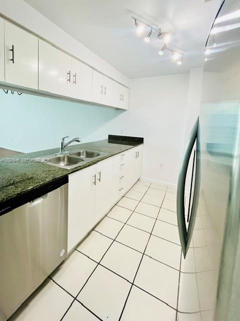 A kitchen features white cabinets, a dark granite countertop, a stainless steel sink, and tile flooring — 1200 Brickell Bay Dr # 4308, Miami FL 33131, MIAMI, FL