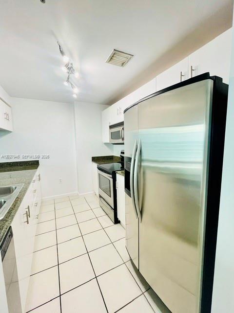 A kitchen features white cabinets, stainless steel appliances, and light-colored tile flooring — 1200 Brickell Bay Dr # 4308, Miami FL 33131, MIAMI, FL