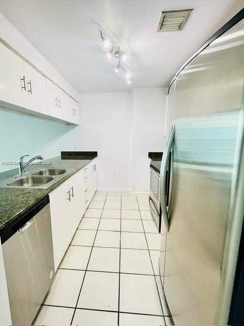 A galley kitchen features white cabinets, dark countertops, stainless steel appliances, and tiled flooring — 1200 Brickell Bay Dr # 4308, Miami FL 33131, MIAMI, FL