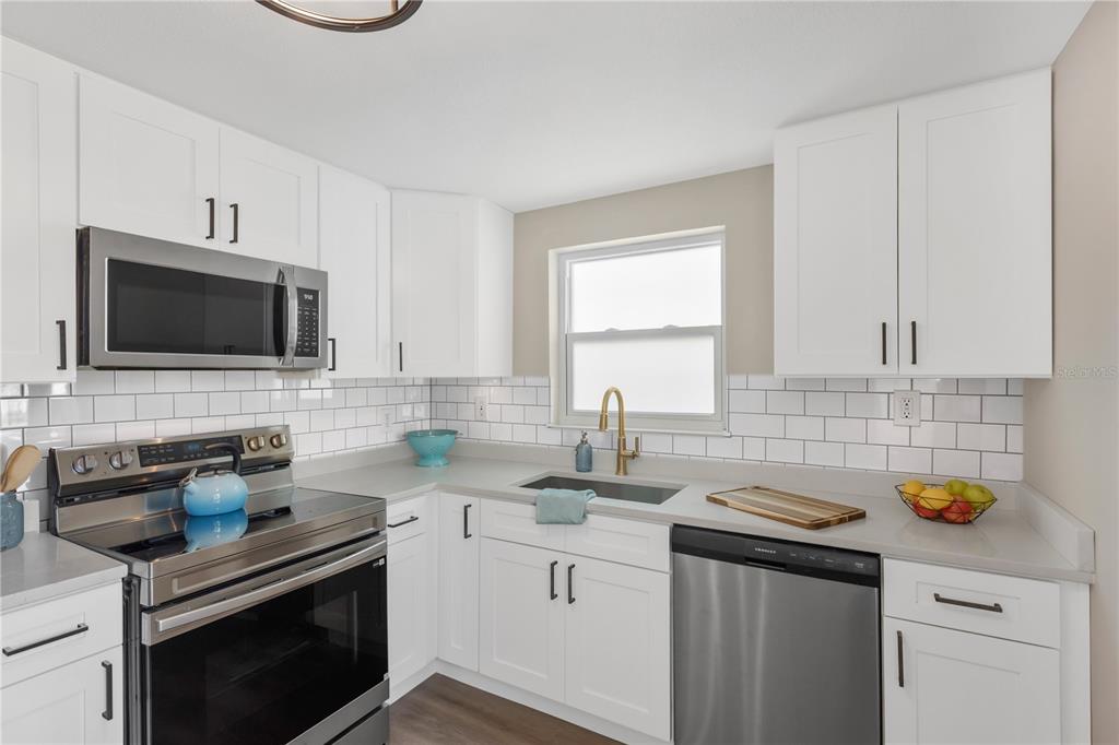 A kitchen with white cabinets, stainless steel appliances, gray countertops, and a white subway tile backsplash — 3111 COLDWELL DRIVE, HOLIDAY, FL