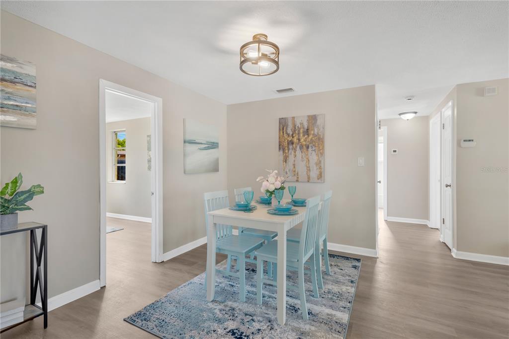 A dining area features a light-colored table with blue chairs on a patterned rug — 3111 COLDWELL DRIVE, HOLIDAY, FL