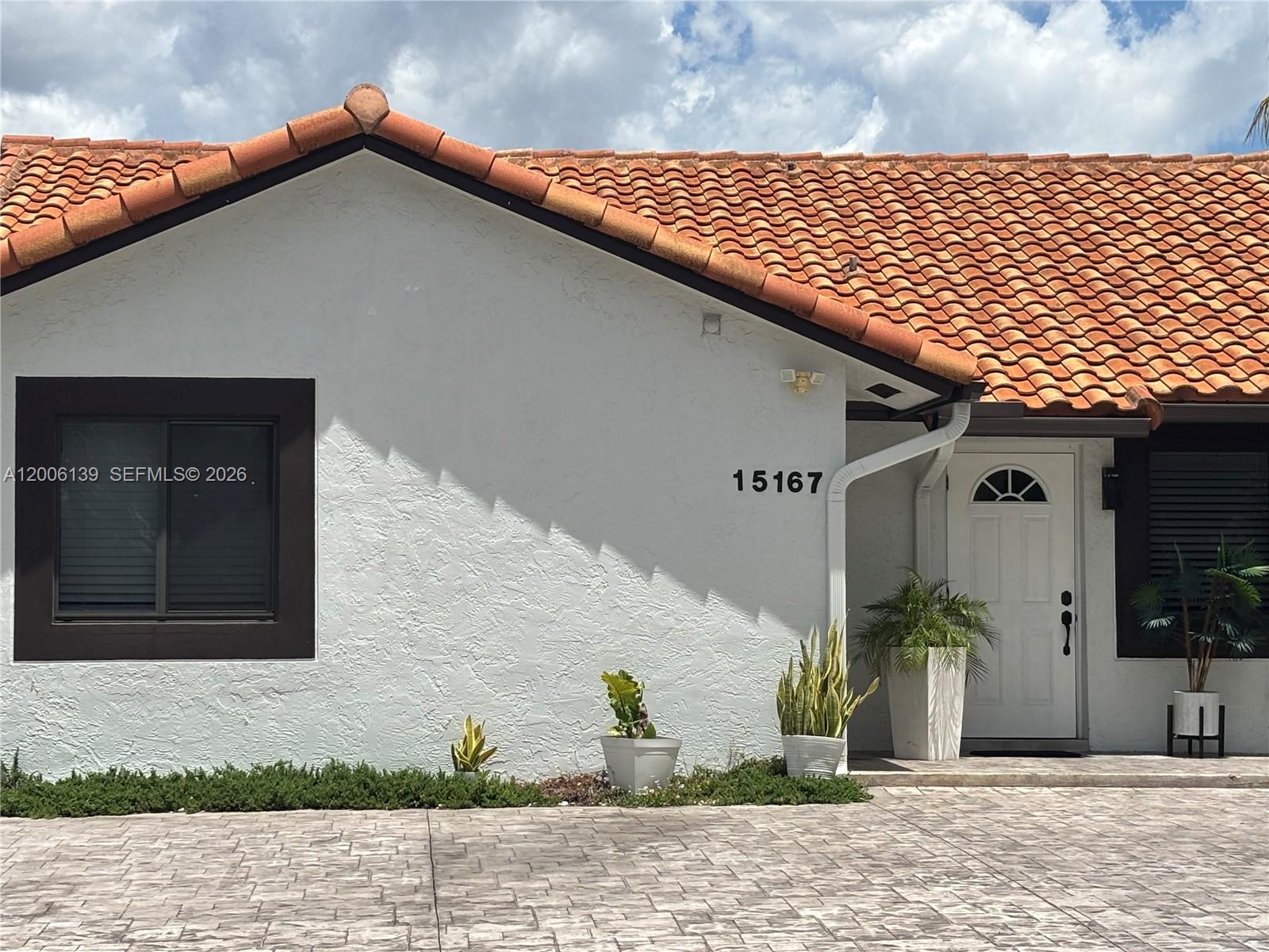The exterior of a white house features a terracotta tile roof and a paved driveway — 15167 SW 94th Ter # 1, Miami FL 33196, MIAMI, FL