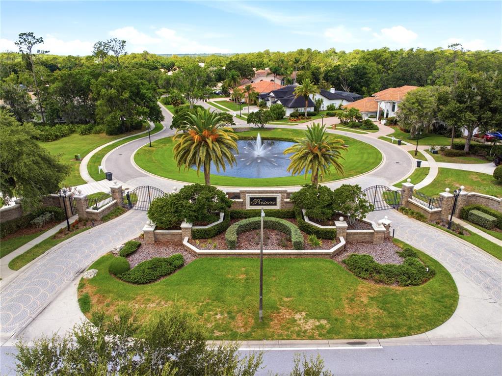 An aerial view of a gated community entrance featuring a fountain and circular driveway — 1332 PRESERVATION WAY, OLDSMAR, FL