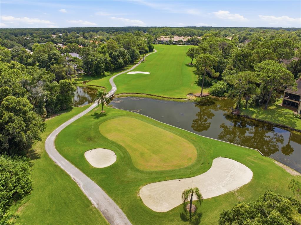 An aerial view of a golf course hole featuring a green, sand bunkers, and water — 1332 PRESERVATION WAY, OLDSMAR, FL
