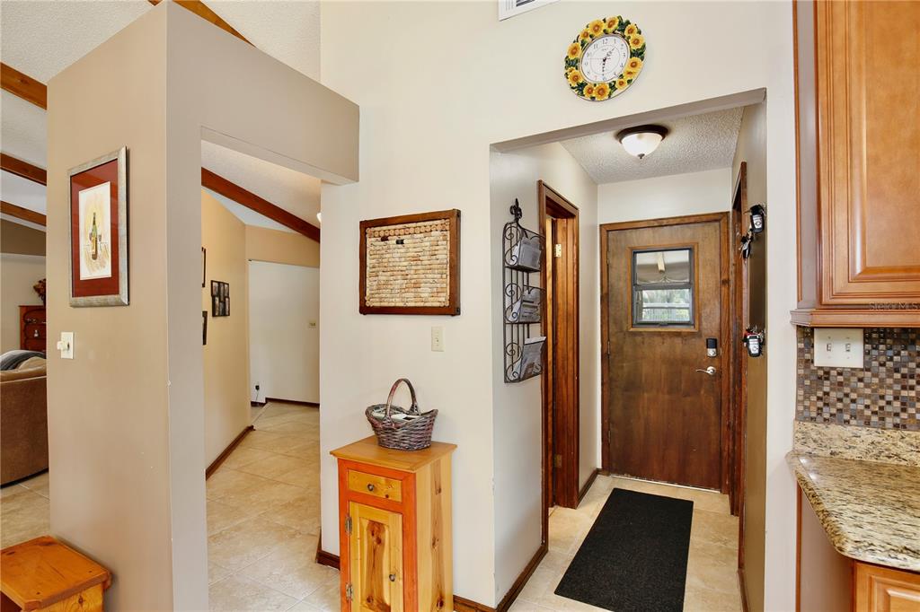 A living room features a brick fireplace, vaulted ceiling with wood beams, and tile flooring — 106 POLO LANE, SANFORD, FL