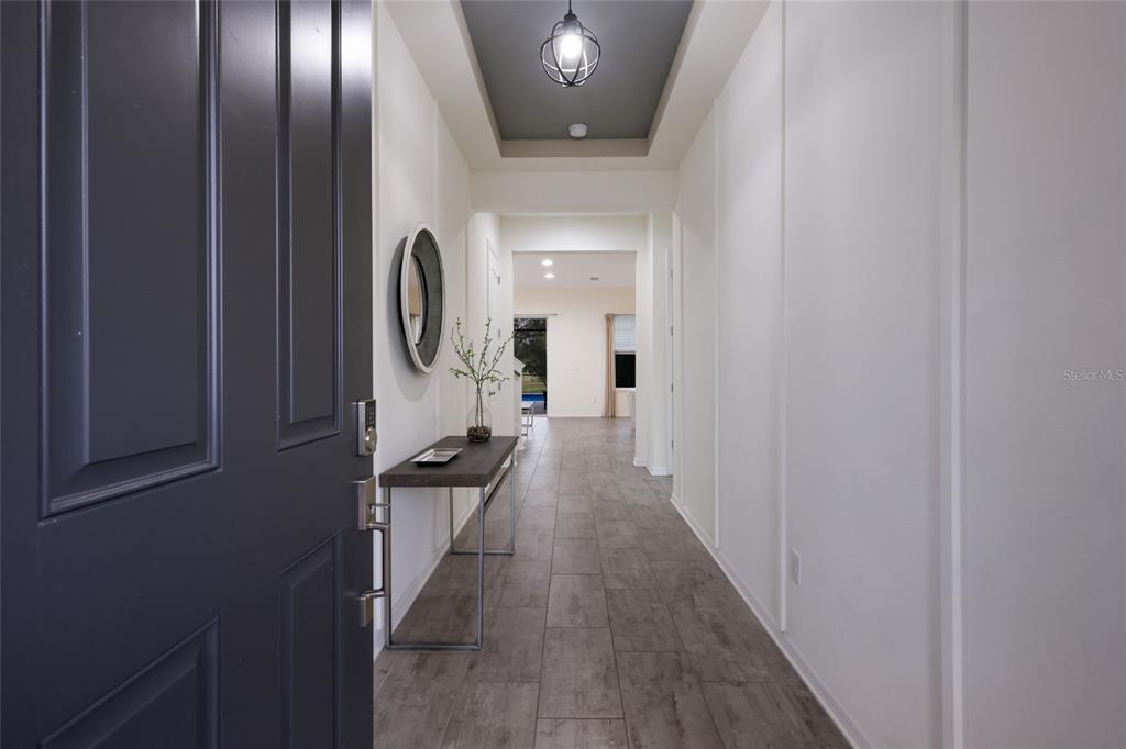 A view from an open dark door into a hallway with gray tile flooring — 13608 AMERICAN PRAIRIE PLACE, LAKEWOOD RANCH, FL