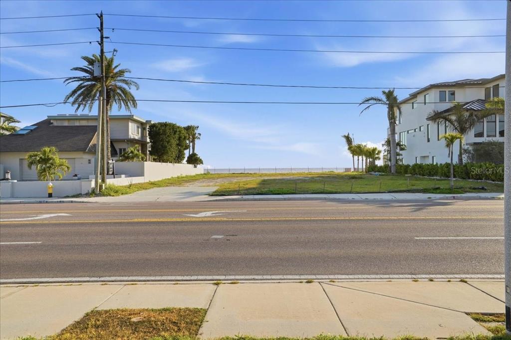 A vacant, grassy residential lot sits between two houses along a paved road — 16007 GULF BOULEVARD, REDINGTON BEACH, FL