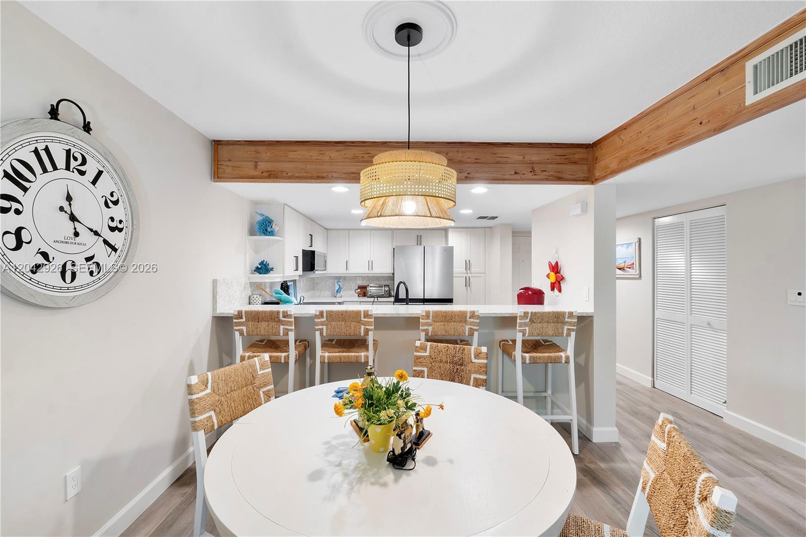 A dining area with a round white table sits in front of a kitchen breakfast bar — 522 Oak Harbour Dr # 522, Juno Beach FL 33408, JUNO BEACH, FL
