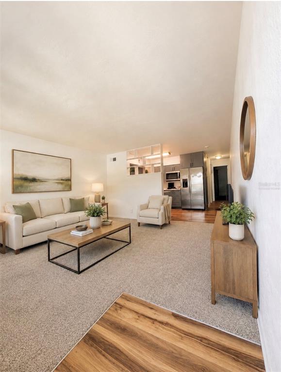 A living room features a beige sofa, a wooden coffee table, and an open kitchen — 4325 58TH WAY N UNIT 1430, KENNETH CITY, FL