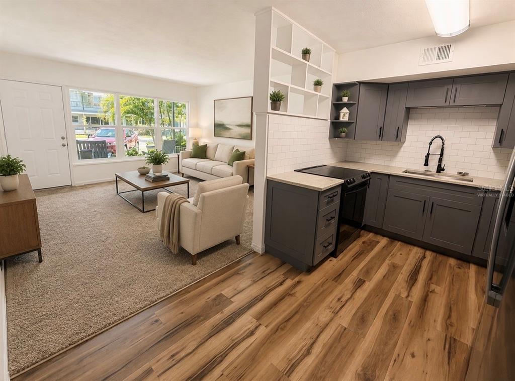 A virtually staged open-concept living room and kitchen with gray cabinets and wood-look flooring — 4325 58TH WAY N UNIT 1430, KENNETH CITY, FL