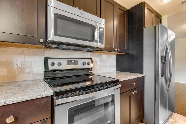 A kitchen features dark wood cabinets, stainless steel appliances, and a light granite countertop — 797 North Drive Unit C, Delray Beach FL 33445, DELRAY BEACH, FL