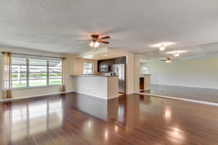 A living room with dark wood flooring, a ceiling fan, and an open kitchen area — 797 North Drive Unit C, Delray Beach FL 33445, DELRAY BEACH, FL