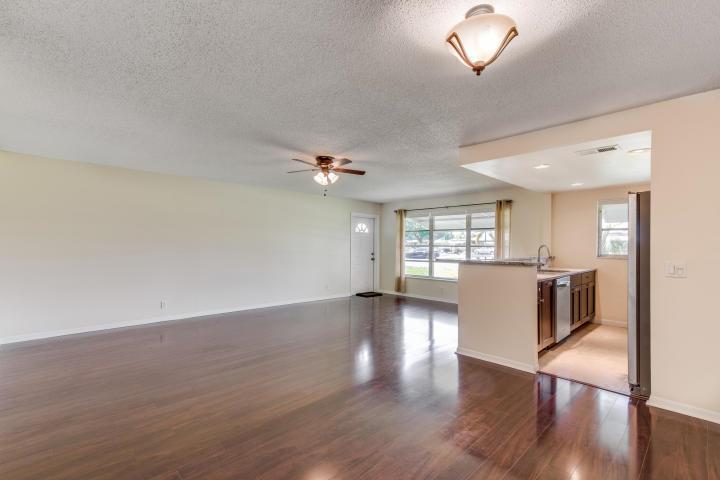 An open-concept living area features dark wood flooring, a ceiling fan, and an adjacent kitchen — 797 North Drive Unit C, Delray Beach FL 33445, DELRAY BEACH, FL