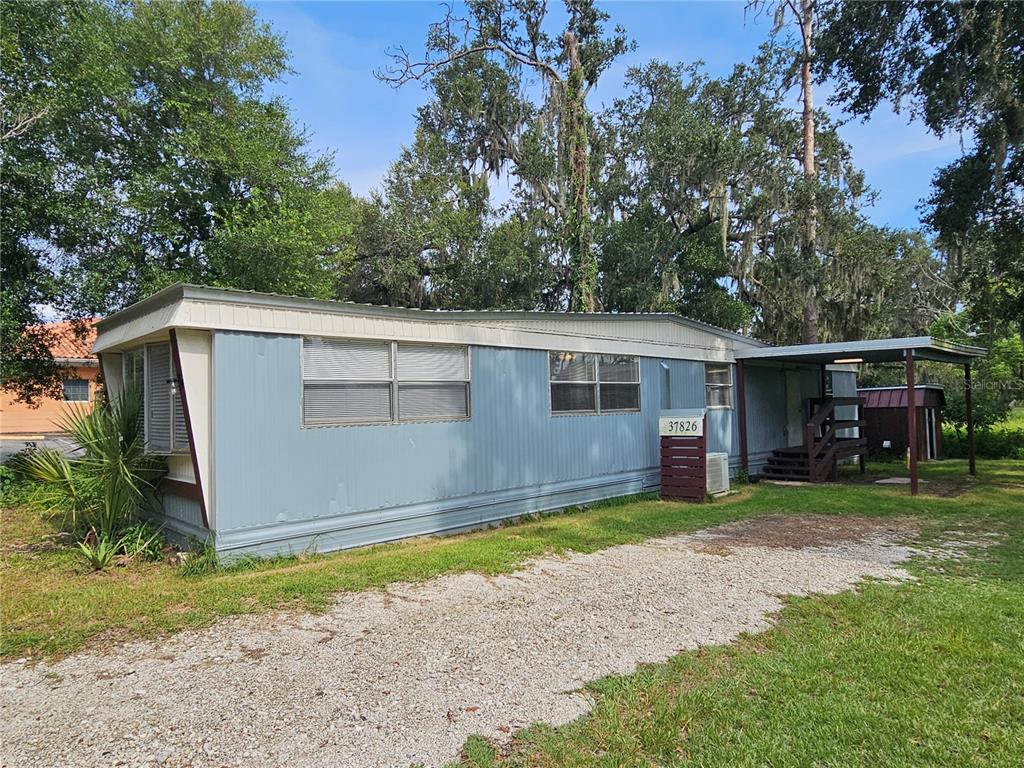 A light blue mobile home with a metal roof and a gravel driveway — 37826 DAUGHTERY ROAD, ZEPHYRHILLS, FL