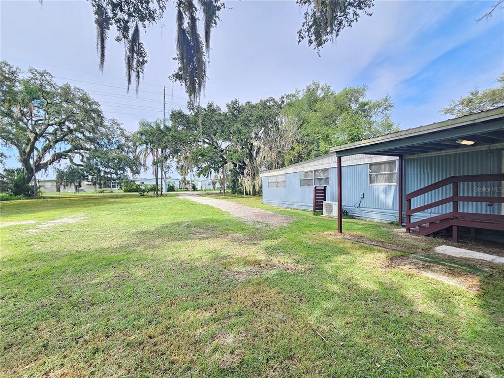 A light blue mobile home with a wooden staircase sits on a grassy lot — 37826 DAUGHTERY ROAD, ZEPHYRHILLS, FL