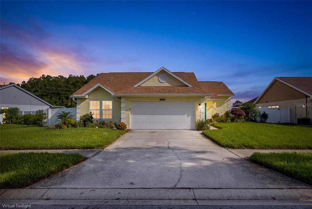 A yellow single-story house with a two-car garage and a brown shingled roof at dusk — 9503 CALLE ALTA, NEW PORT RICHEY, FL