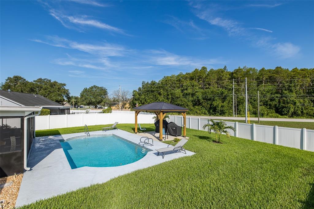 A backyard features a swimming pool, a wooden gazebo, and a white privacy fence — 9503 CALLE ALTA, NEW PORT RICHEY, FL