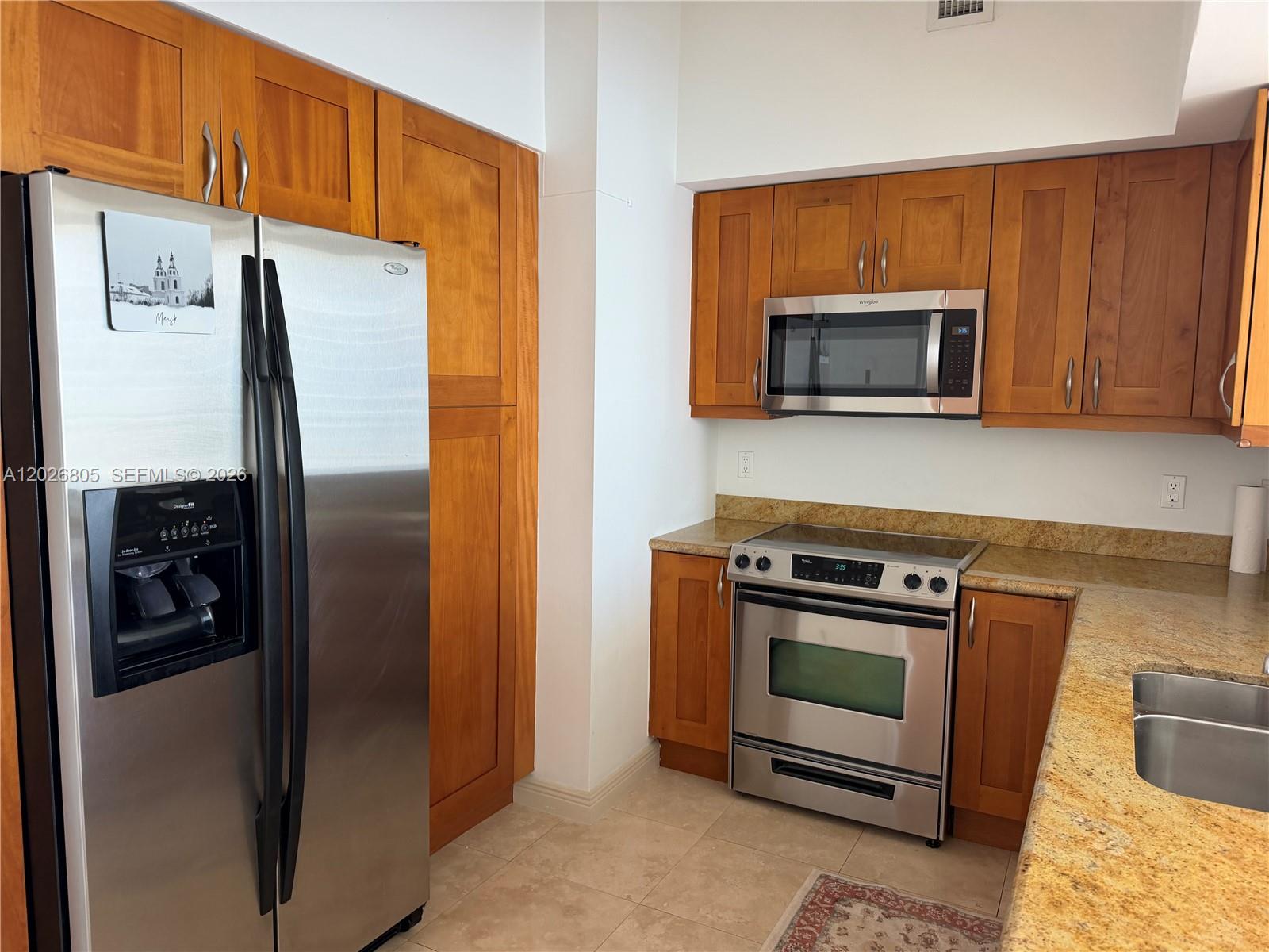 A kitchen with stainless steel appliances, wood cabinets, and granite countertops — 1755 E Hallandale Beach Blvd # 2404E, Hallandale Beach FL 33009, HALLANDALE BEACH, FL