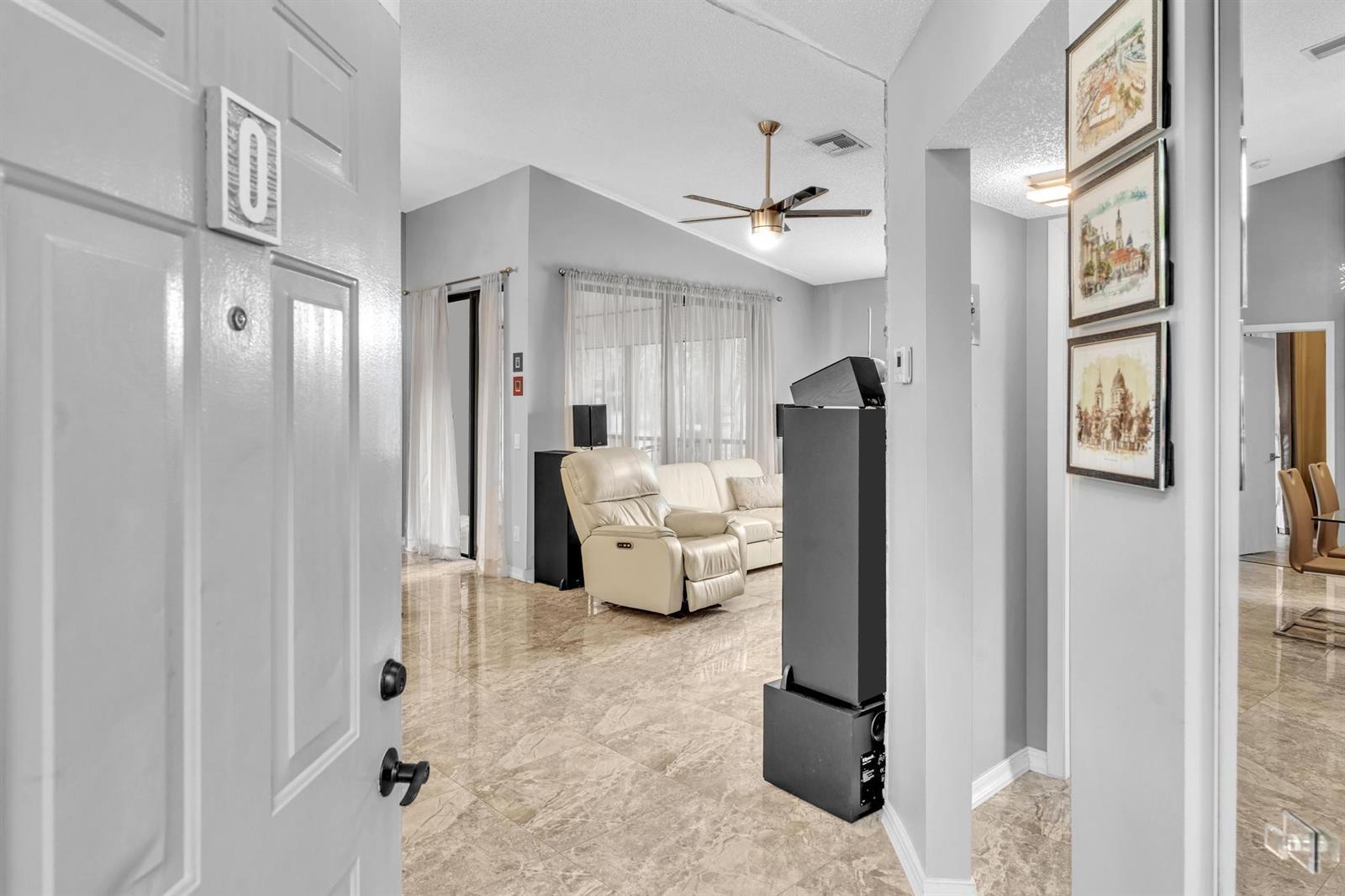 A view from an open doorway into a living room with tile floors and furniture — 5395 Firenze Drive # O, Boynton Beach FL 33437, BOYNTON BEACH, FL