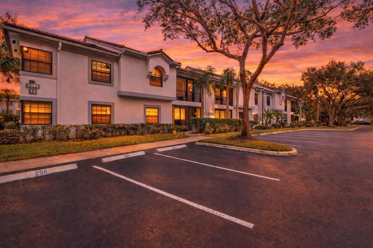 A two-story apartment building exterior with a parking lot at sunset — 5395 Firenze Drive # O, Boynton Beach FL 33437, BOYNTON BEACH, FL