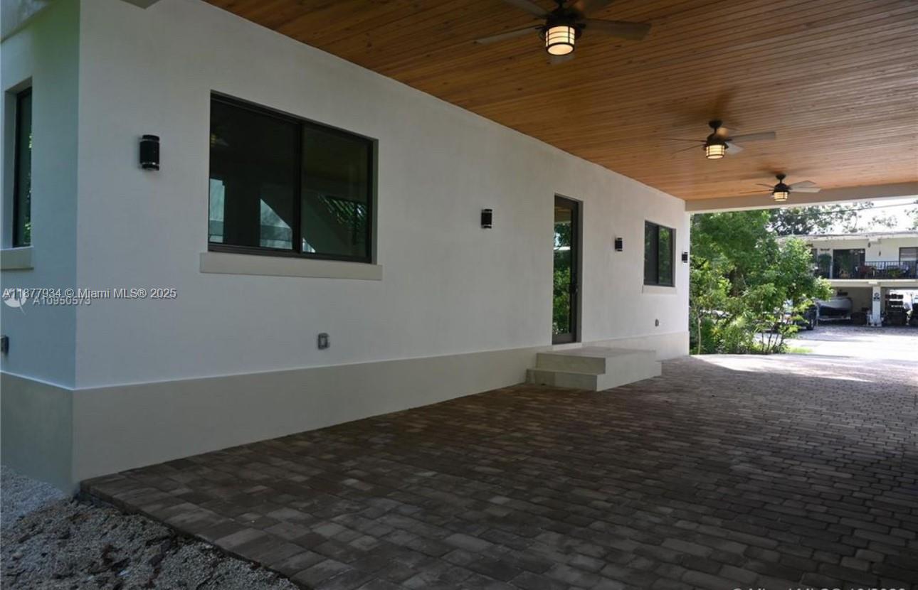 A covered patio with a wood-paneled ceiling, ceiling fans, and a brick paver floor — 14 Coral Dr # 1, Key Largo FL 33037, KEY LARGO, FL