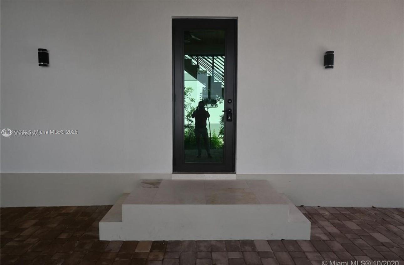 A single glass-paneled door is centered above a small concrete step on a patio — 14 Coral Dr # 1, Key Largo FL 33037, KEY LARGO, FL