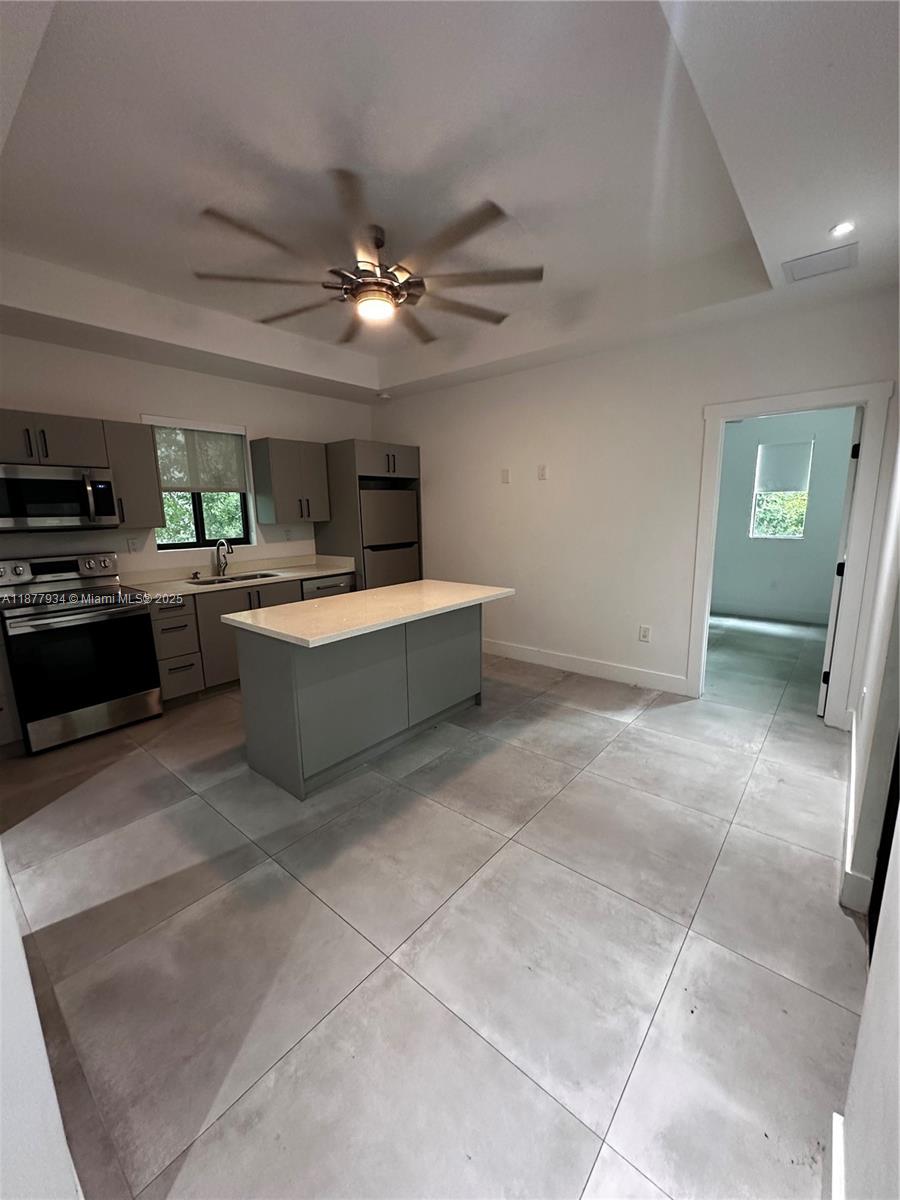 A kitchen features gray cabinets, stainless steel appliances, a center island, and large floor tiles — 14 Coral Dr # 1, Key Largo FL 33037, KEY LARGO, FL