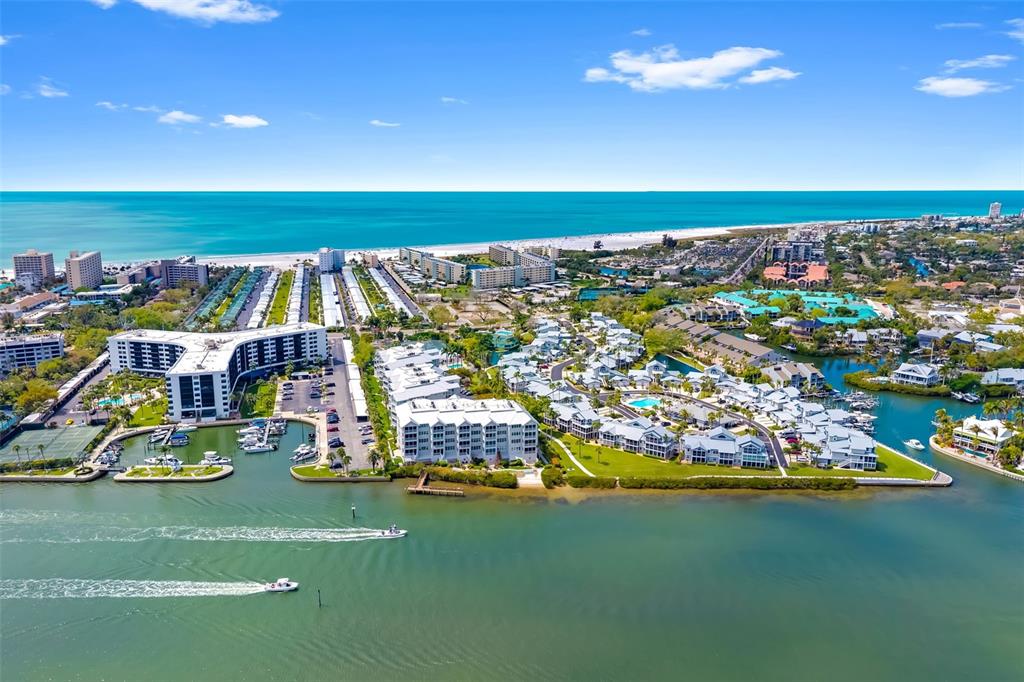 An aerial view shows a coastal resort complex with multiple buildings, swimming pools, and docks — 1280 DOLPHIN BAY WAY UNIT 504, SARASOTA, FL