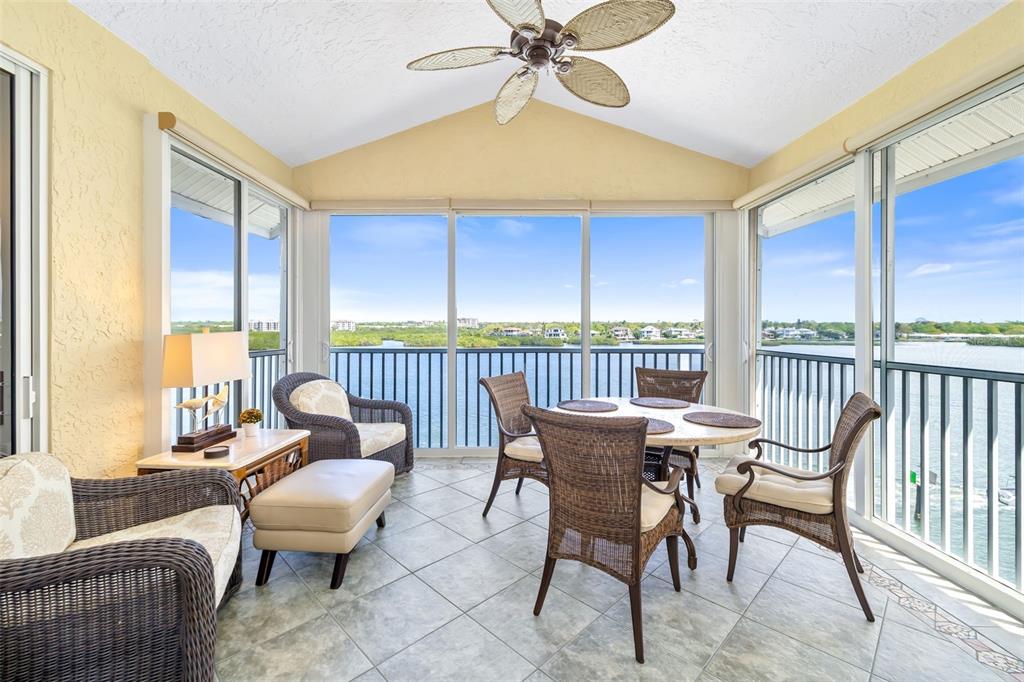 A sunroom with wicker furniture, tile floors, and large windows overlooking a body of water — 1280 DOLPHIN BAY WAY UNIT 504, SARASOTA, FL