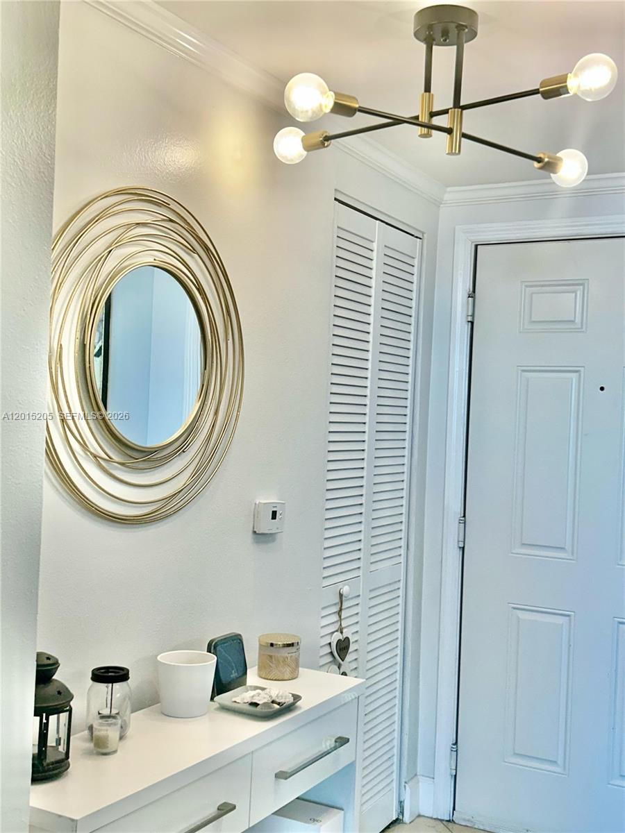 A white entryway features a modern gold chandelier, a circular mirror, and a console table — 625 Casa Loma Blvd # 1009, Boynton Beach FL 33435, BOYNTON BEACH, FL